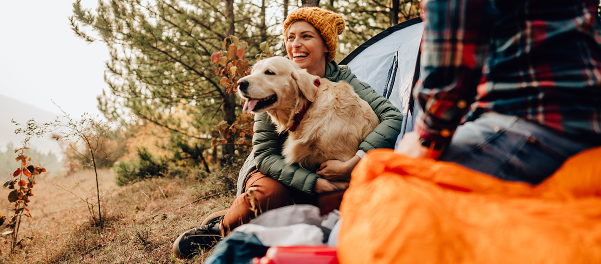 Frau umarmt Hund vor Zelt Frau umarmt Hund vor Zelt