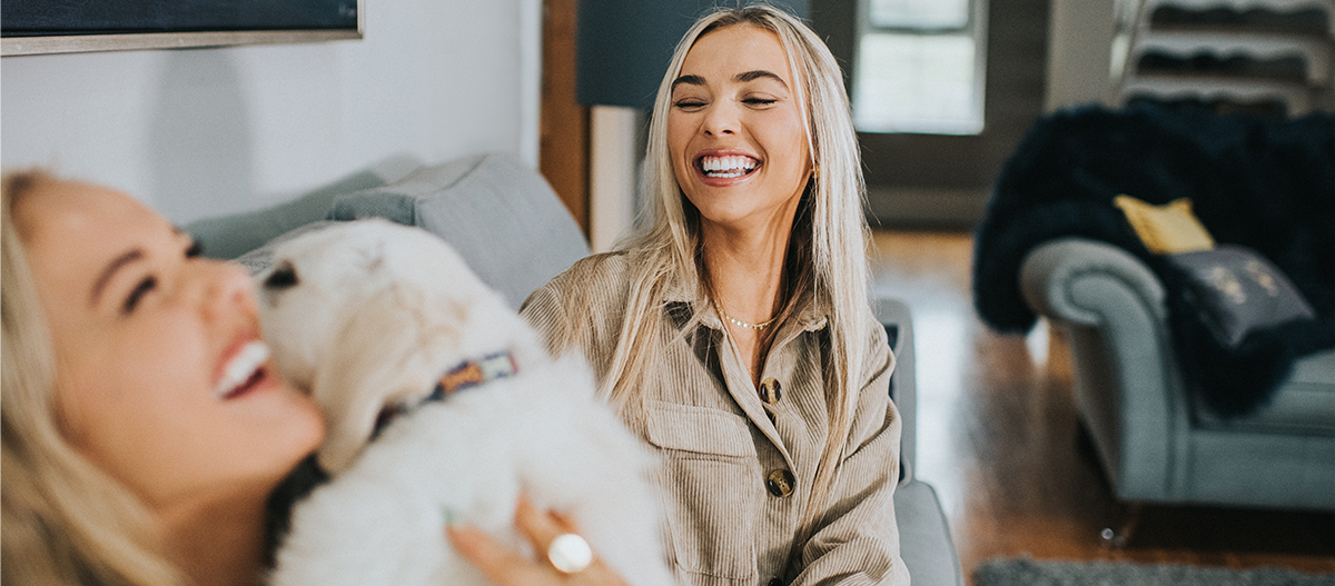 Zwei Frauen kuscheln mit Welpe auf Sofa Zwei Frauen kuscheln mit Welpe auf Sofa