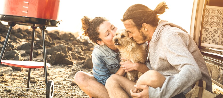 Paar sitzt mit Hund am Strand Paar sitzt mit Hund am Strand