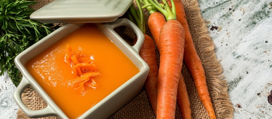 Eine cremige Karottensuppe in einer Schale auf einem Tisch. Eine cremige Karottensuppe in einer Schale auf einem Tisch.