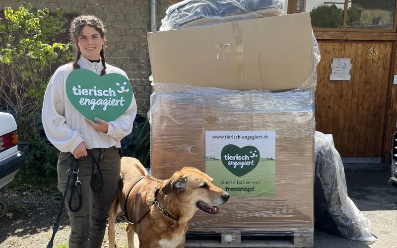 Eine Frau und ihr Hund vor Spendenpaletten für tierisch engagiert