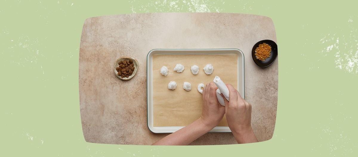 Hände mit Spritzbeutel, Backblech mit Baisers, links Schale mit Leckerlies, rechts Schale mit Leckerlies Hände mit Spritzbeutel, Backblech mit Baisers, links Schale mit Leckerlies, rechts Schale mit Leckerlies